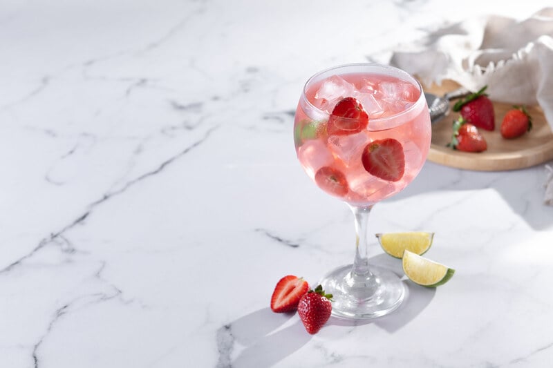 Sparkling strawberry cocktail with fresh strawberries and lime in balloon glass