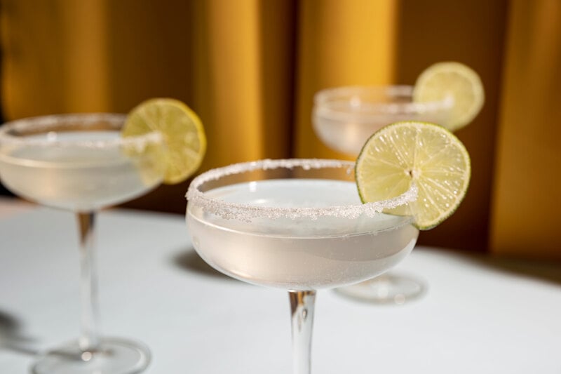 Champagne margaritas in coupe glasses with salted rim and lime garnish