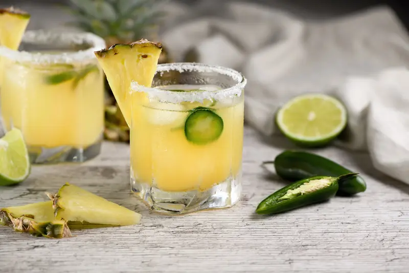 Pineapple jalapeño margarita with salted rim, fresh pineapple wedge and jalapeño slices