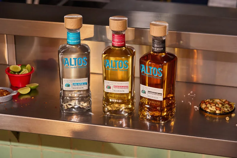 three bottles of altos tequila, plata, reposado and añejo, displayed on a bar counter

