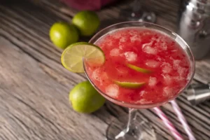 frozen watermelon margarita with lime slices and crushed ice in a margarita glass
