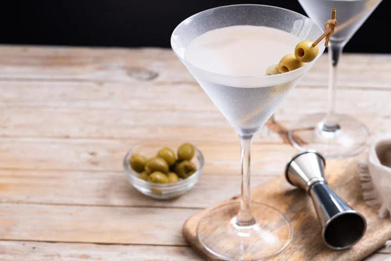 dirty martini with tequila and olives served in chilled martini glass on wooden table