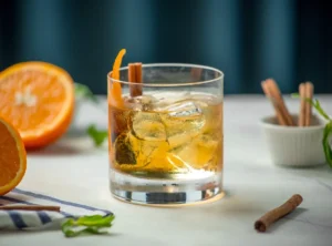 tequila white negroni con hielo, piel de naranja y rama de canela en vaso bajo