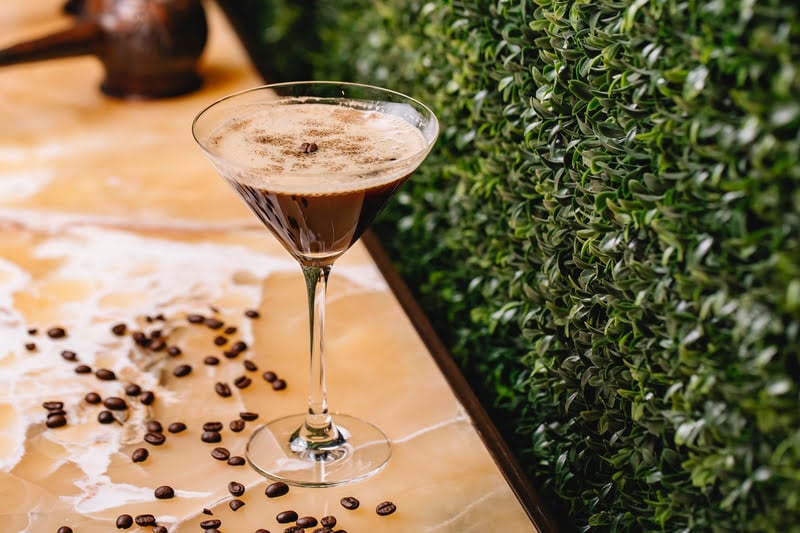 Mexican chocolate martini in a martini glass, topped with cocoa and garnished with coffee beans on the table.